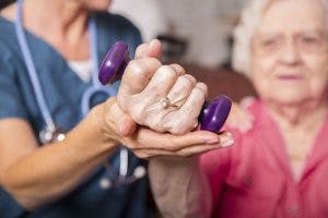 Therapeutin trainiert mit alter Frau mit Hantel