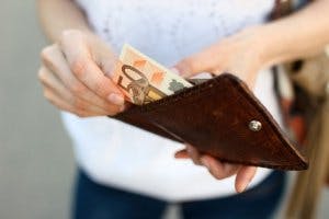 Foto von Frau, die einen Fünzig-Euro-Schein aus ihrem Portemonnaie holt